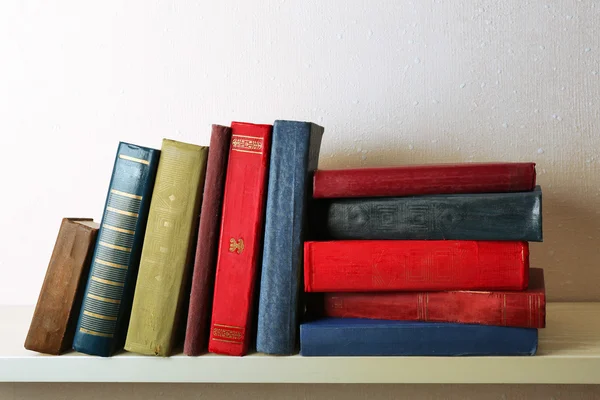 Old books on shelf, close-up, on light wall background — Stock Photo, Image