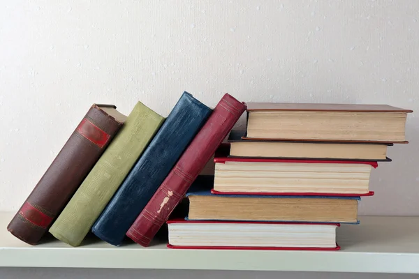 Buku-buku tua di rak, close-up, di dinding cahaya latar belakang — Stok Foto