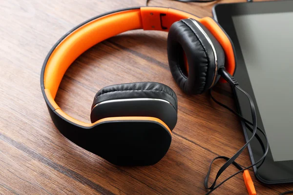 Auriculares con tablet en mesa de madera de cerca —  Fotos de Stock