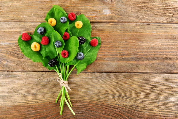 Dojrzałe owoce smaczne na zielonych liści na drewniane tła — Zdjęcie stockowe