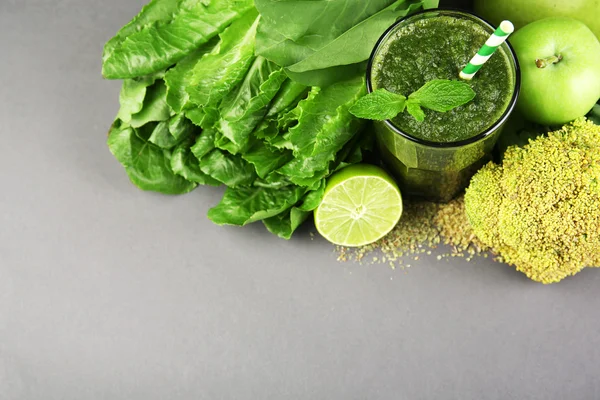 Succo sano verde con frutta e verdura su sfondo grigio — Foto Stock