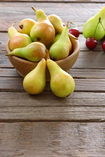 Rijpe peren en kersen op houten tafel close-up — Stockfoto