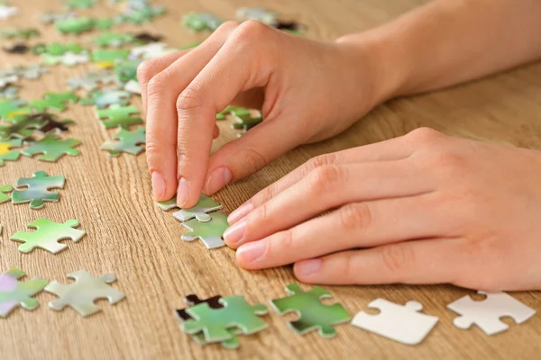 Female hands assembling puzzle — Stock Photo, Image