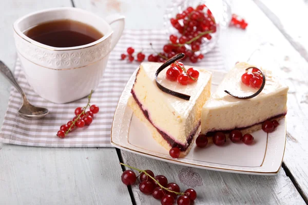 Leckerer Käsekuchen mit Beeren und einer Tasse Tee auf dem Tisch aus nächster Nähe — Stockfoto