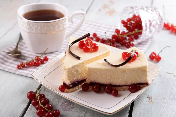 Smakelijke cheesecake met bessen en kopje thee op tafel close-up — Stockfoto
