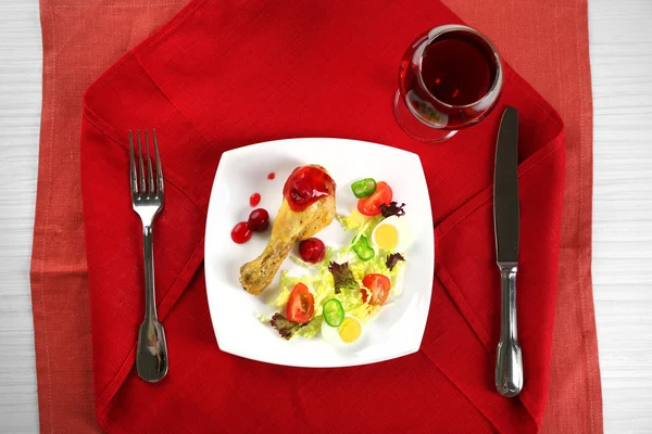 Gericht gebackene Hähnchenkeule und Gemüsesalat in weißem Teller mit Glas Wein auf Tisch mit Serviette, Draufsicht — Stockfoto