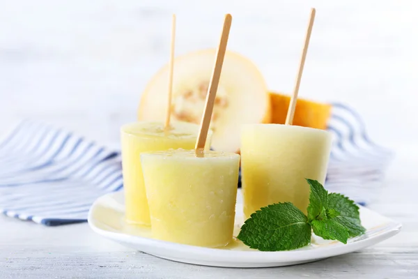 Melon lody na patyku na stole na jasnym tle niewyraźne — Zdjęcie stockowe