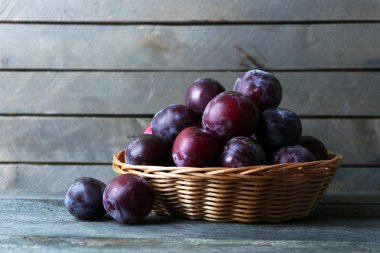 Ahşap arka plan üzerinde sepette lezzetli olgun Erik