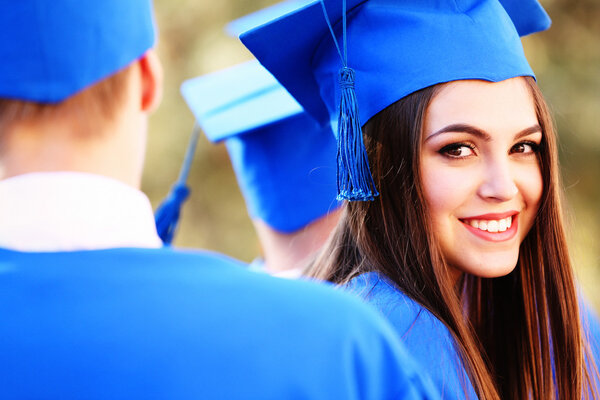 Graduated students in graduation hats and gowns, outdoors