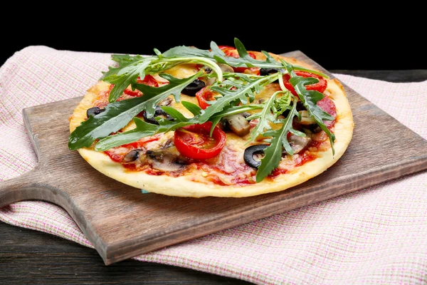 Leckere Pizza mit Gemüse und Rucola auf Schneidebrett auf dem Tisch aus nächster Nähe — Stockfoto