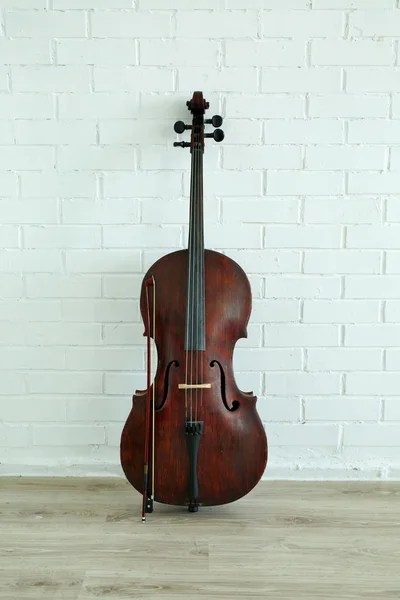 Cello på vit tegelvägg — Stockfoto