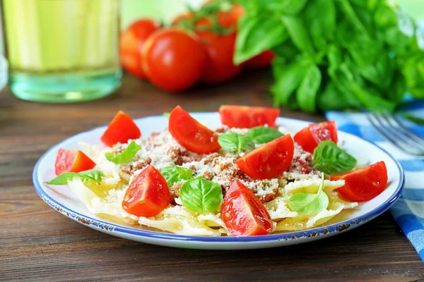 Pasta bolognese with cherry tomatoes in white plate on wooden table, closeup — Stock Photo, Image