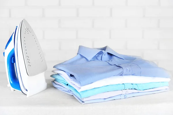 Electronic ironing and pile of clothes — Stock Photo, Image