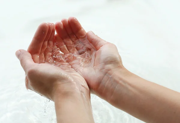 Vrouwelijke handen over helder water — Stockfoto