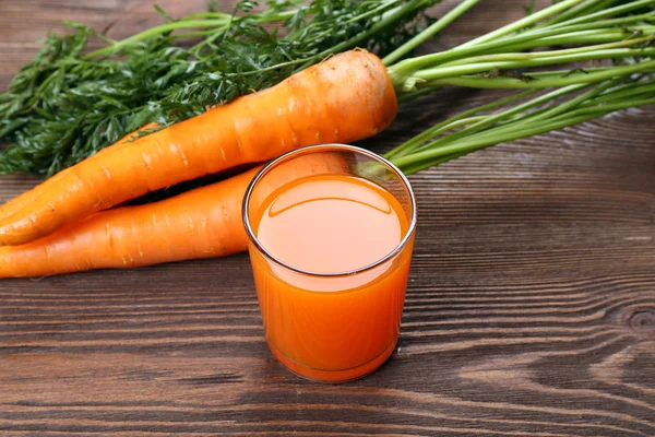 Glas morotsjuice med grönsaker på träbord nära håll — Stockfoto