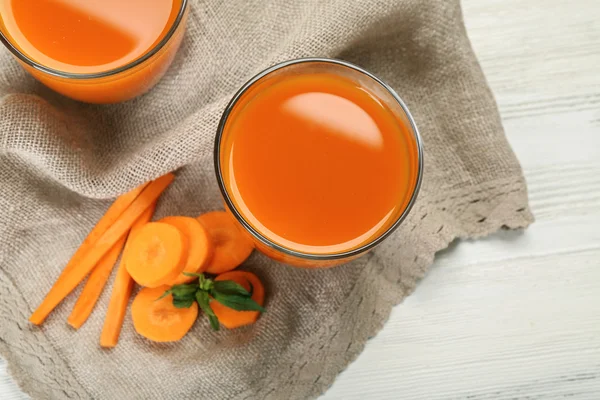 Verres de jus de carotte avec tranches de légumes sur la table close up — Photo