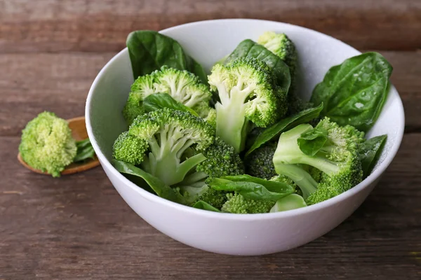 Broccoli freschi con spinaci in ciotola sul tavolo di legno da vicino — Foto Stock