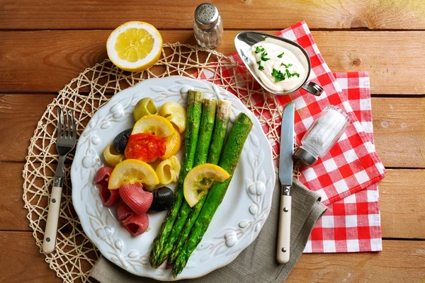 Жареная спаржа и вкусная красочная макароны с овощами на тарелке на фоне деревянного стола — стоковое фото