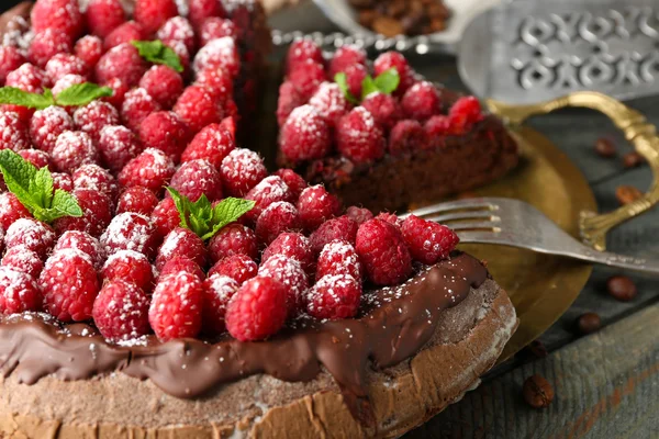 Kuchen mit Schokoglasur und Himbeeren auf Holzgrund — Stockfoto