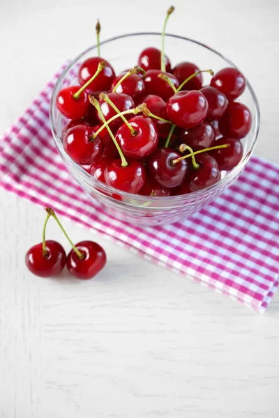 Cherries in glass bowl on table, on light background — Stock Photo, Image