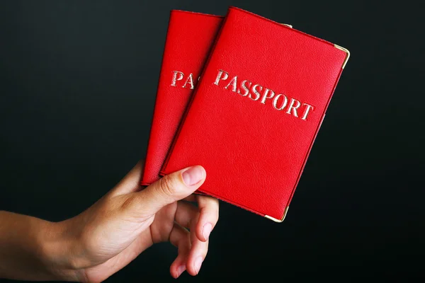 Γυναικείο χέρι, κρατώντας τα διαβατήρια σε σκούρο φόντο — Φωτογραφία Αρχείου