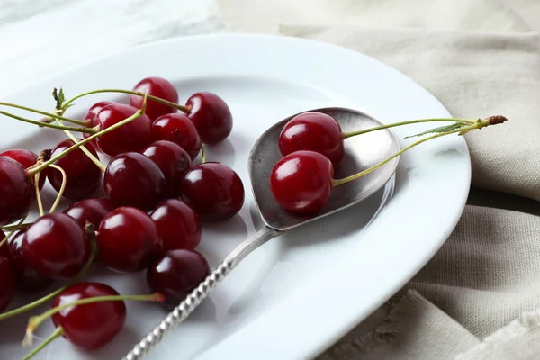 Sweet cherries on plate, on wooden background — Stock Photo, Image