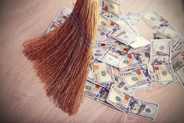 Dollars and broom on wooden floor — Stock Photo, Image