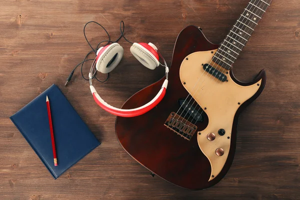 Guitarra elétrica com fones de ouvido e notebook na mesa de madeira de perto — Fotografia de Stock