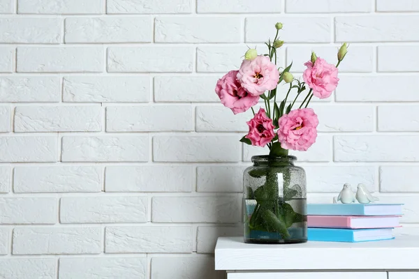 Hermosas flores con libros sobre fondo de pared de ladrillo —  Fotos de Stock