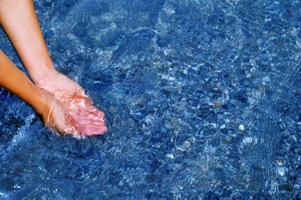 Женская рука касается голубой воды . — стоковое фото