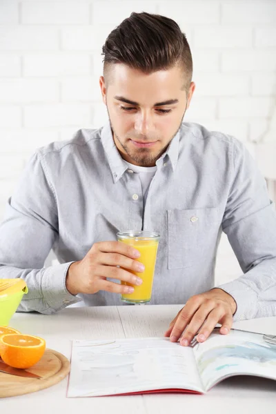 Joven con una mesa llena de naranjas frescas y jugo — Foto de Stock