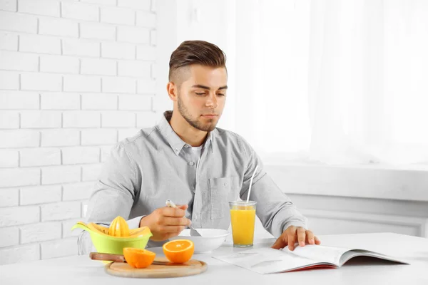 Νεαρός άνδρας, έχοντας πρωινό με πορτοκάλια — Φωτογραφία Αρχείου