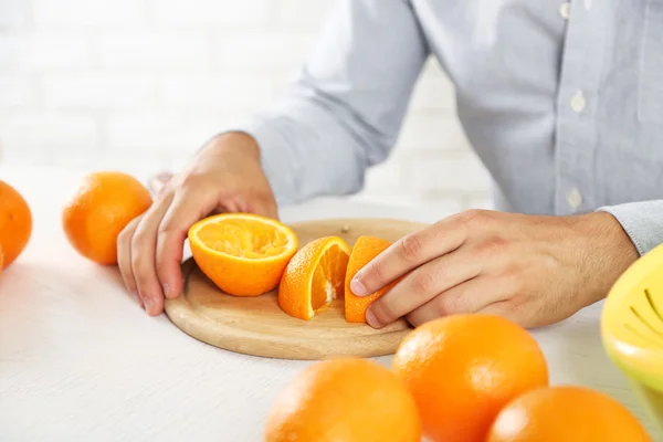 Hombre joven cortando naranjas, preparando jugo de naranja —  Fotos de Stock