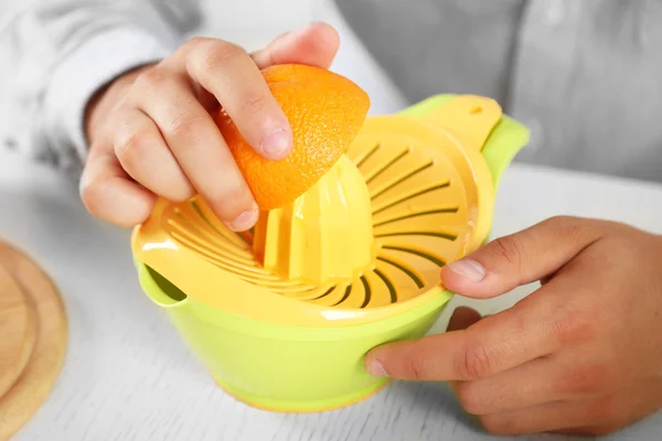 Jovem usando espremedor de frutas cítricas, preparando suco de laranja — Fotografia de Stock
