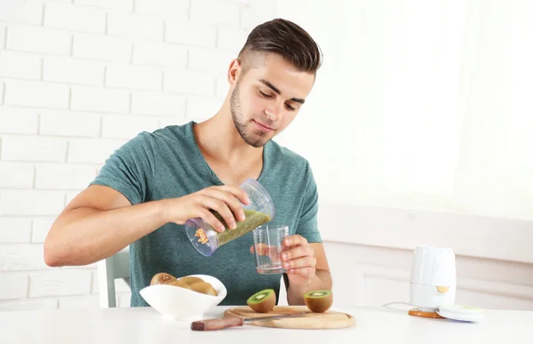 Jeune homme versant du jus de kiwi frais dans du verre — Photo