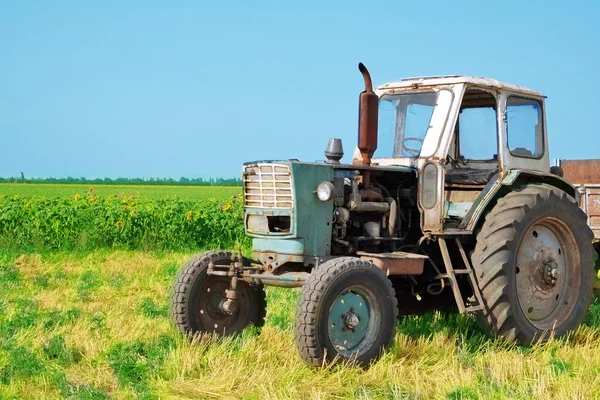 Трактор в поле на голубом фоне неба — стоковое фото