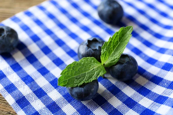 Tasty ripe blueberries with mint on fabric background — Stock Photo, Image