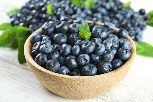 Leckere reife Blaubeeren mit Minze in Schüssel auf dem Tisch aus nächster Nähe — Stockfoto