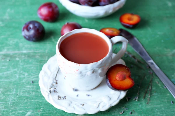 Läckra plommon juice med frukter på träbord nära håll — Stockfoto