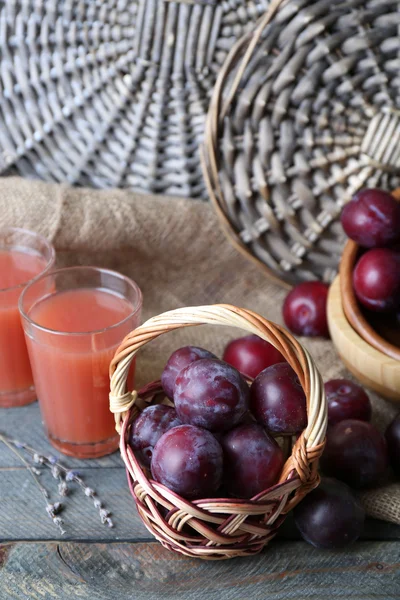 Heerlijke pruim SAP met vruchten op rieten achtergrond — Stockfoto