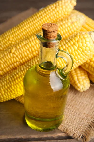 Fresh corn with bottle of oil on table close up — Stock Photo, Image