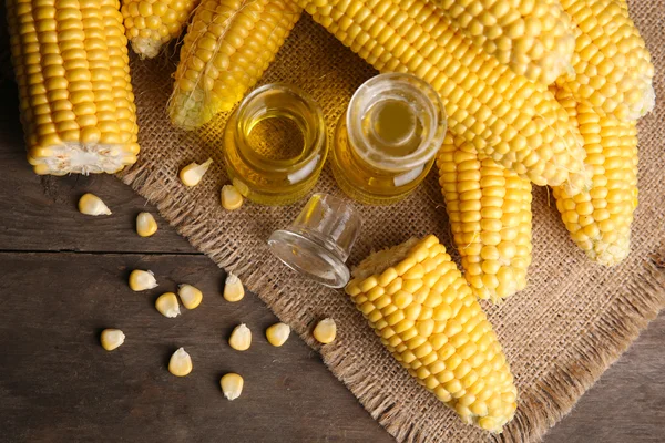 Fresh corn with bottles of oil on table close up — Stock Photo, Image