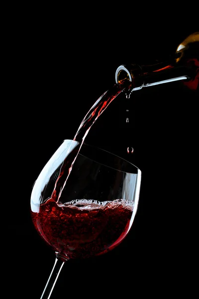 Red wine pouring into wine glass on black background — Stock Photo, Image