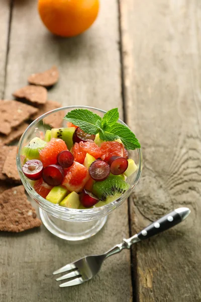 Fruit salad in glass bowl, on wooden background — Stock Photo, Image