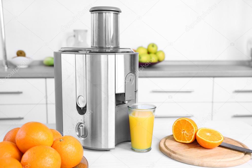 Juicer and fruits on table in kitchen, close up