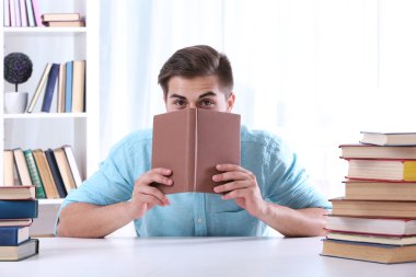 Genç adam masada kitap okumak