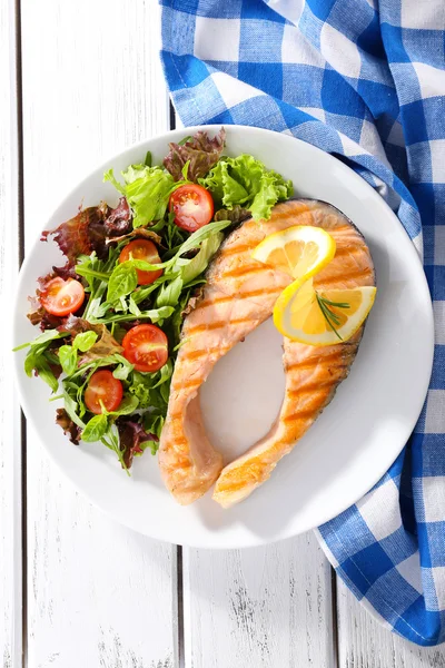 Salmão grelhado saboroso com salada na mesa de perto — Fotografia de Stock