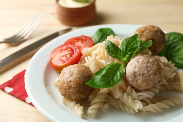 Pâtes avec boulettes de viande sur assiette, sur fond de table en bois — Photo