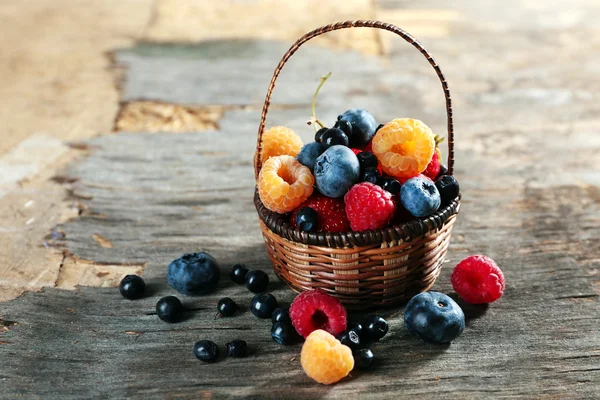 Sweet tasty berries in basket on wooden table close up — Stock Photo, Image