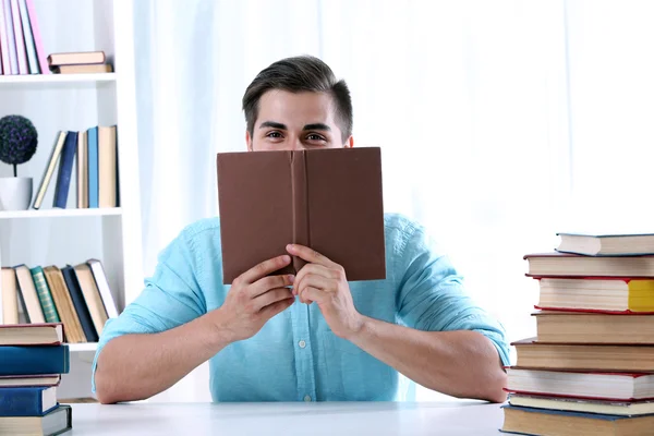 Young man reading book at table — Stock Photo, Image